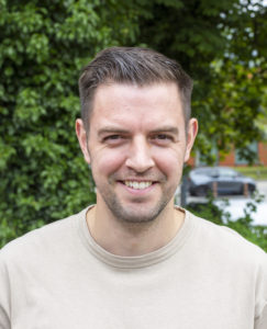 Paul Baddock. white male, smiling in a baige jumper